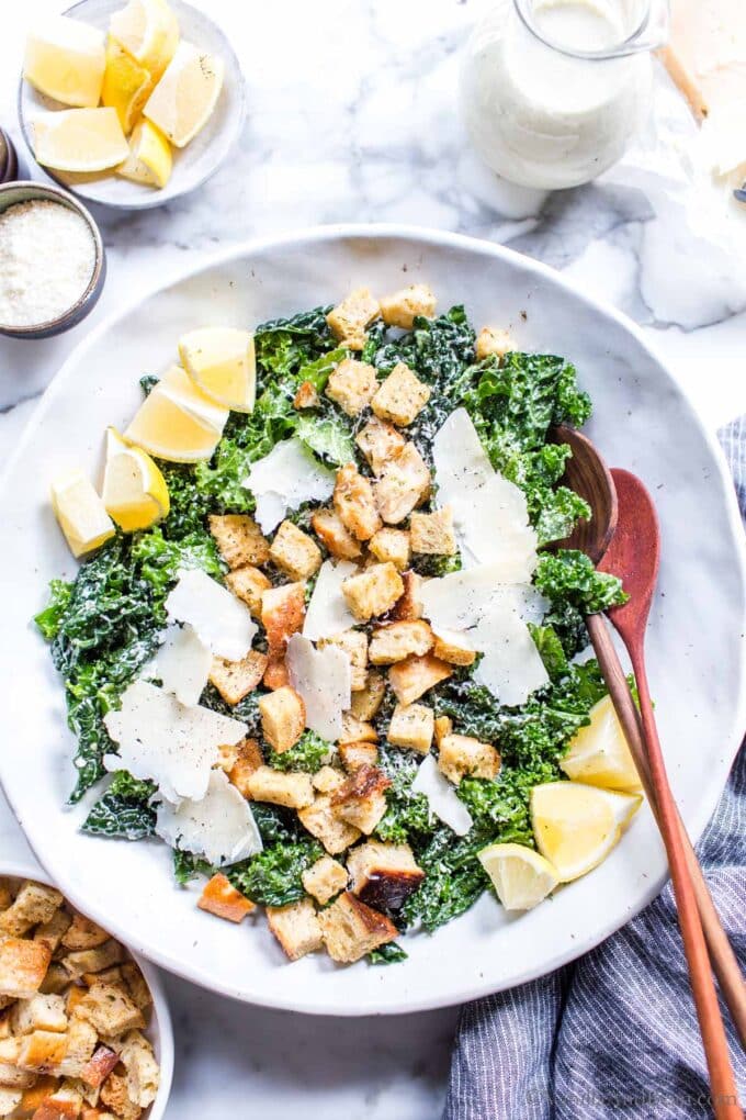 Vegetarian Kale Caesar Salad with croutons, lemons and cheese in a bowl.