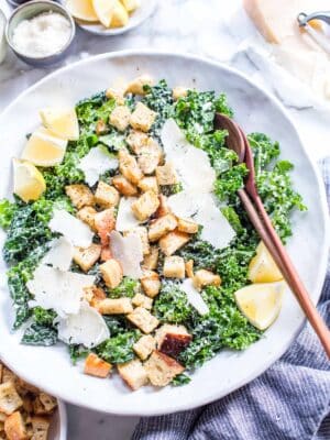 Vegetarian Kale Caesar Salad with croutons, lemons and cheese in a bowl.