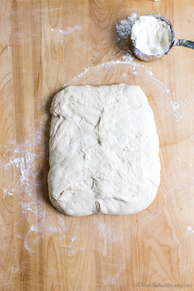 Shaping sourdough by creating the shape of a rectangle.