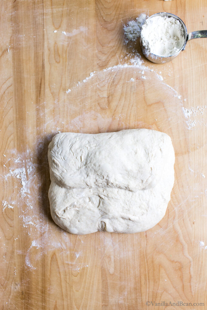 Shaping rustic sourdough bread by folding the dough like a letter and creasing it in the center.