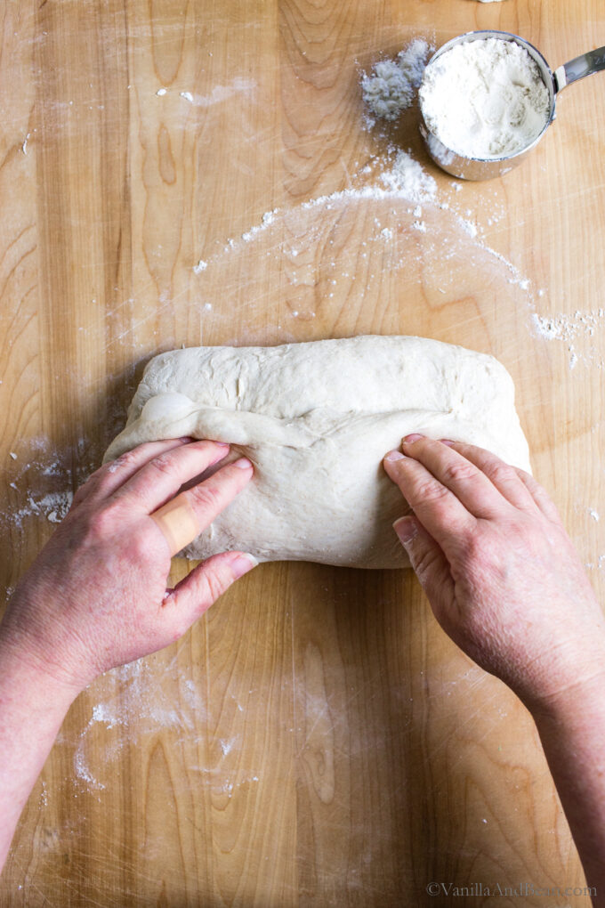 Shaping rustic sourdough bread by folding the dough like a letter and creasing it in the center.