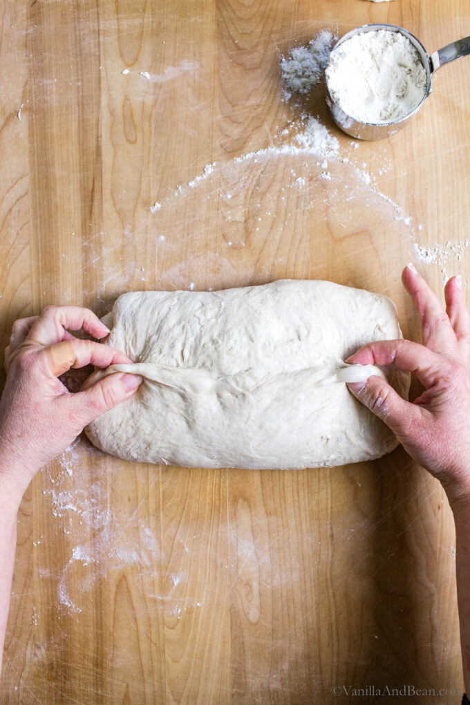 Shaping rustic sourdough bread by folding the dough like a letter and creasing it in the center