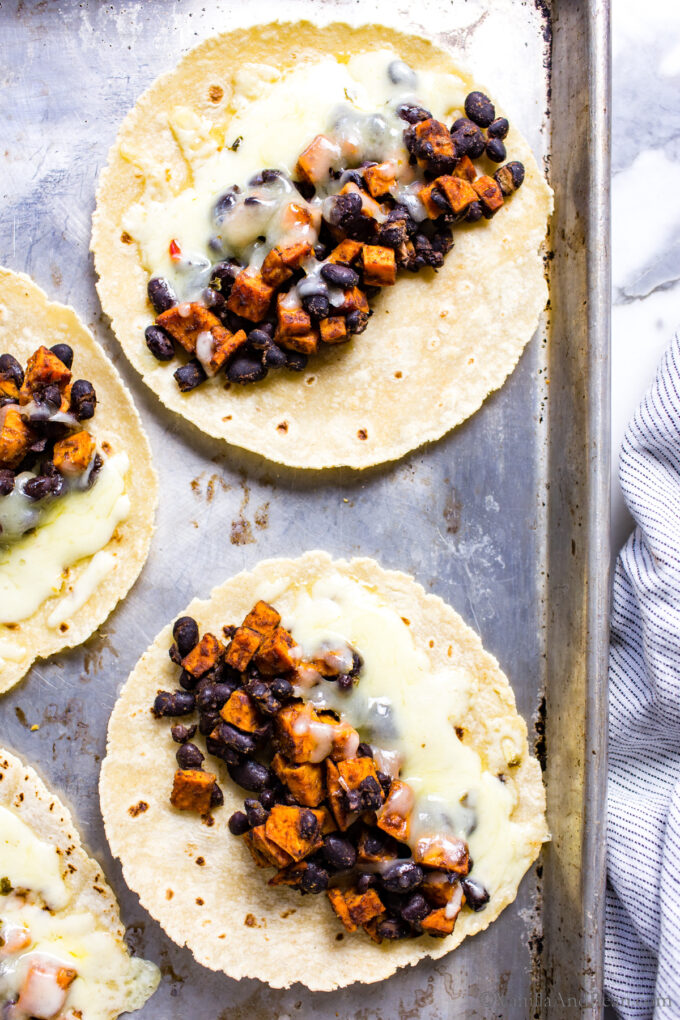 Black Bean and Sweet Potato Tacos on a sheet pan after baking- the cheese is melted.