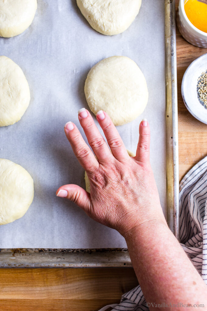 Shaping Sourdough Burger Buns by pressing the dough into the pan to flatten.