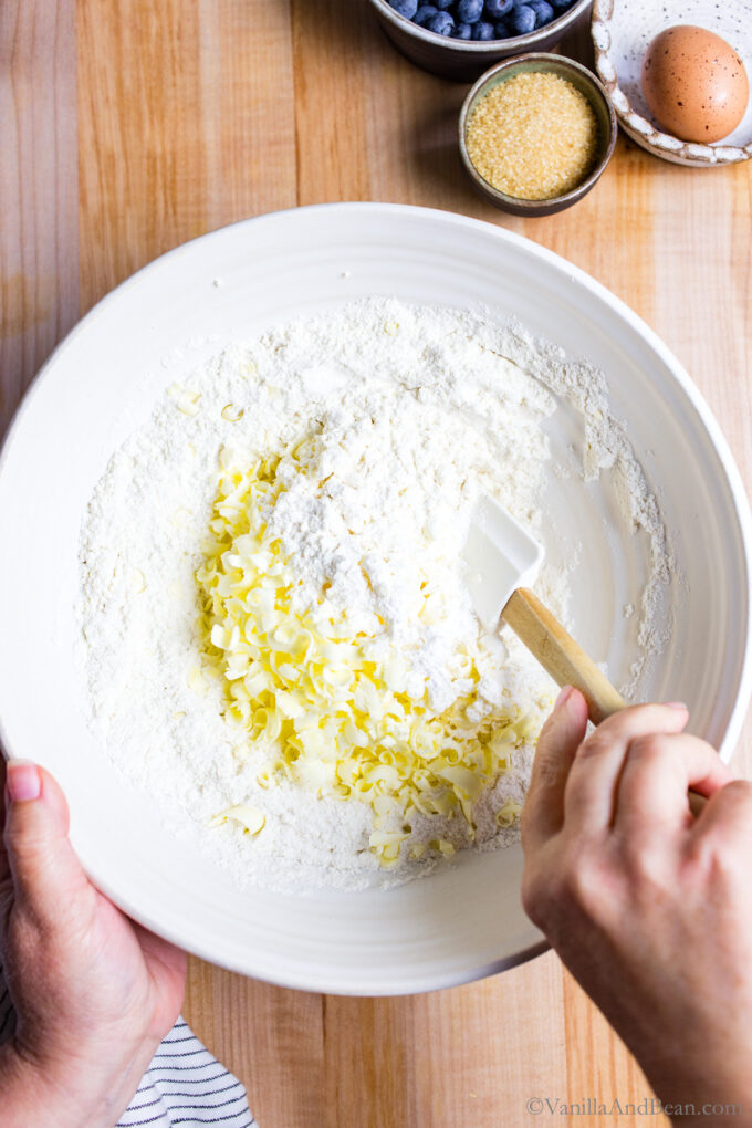 Mixing butter with dry ingredients in a bowl.