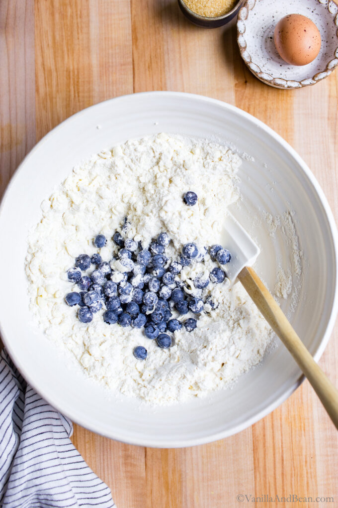 Mixing dry ingredients with fresh blueberries.