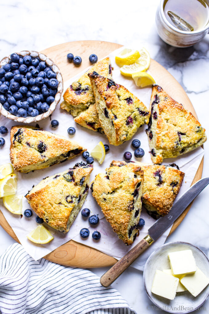 Lemon Blueberry Sourdough Scones on a serving platter with a knife and butter on the side. 