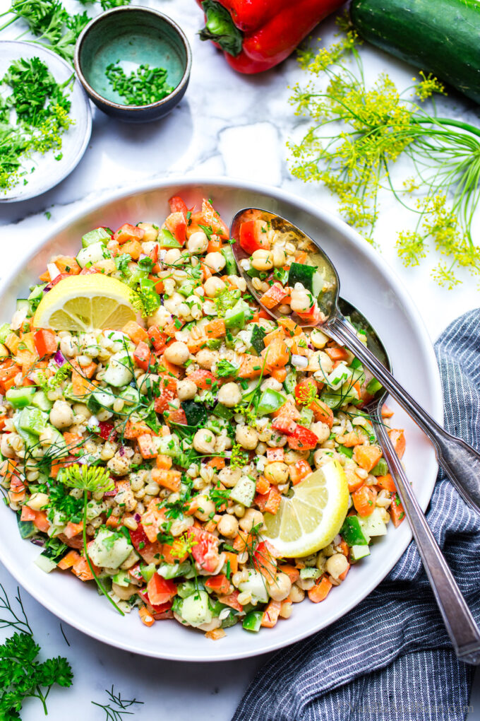 Chickpea Summer salad in a serving bowl with spoons on the side for serving. 