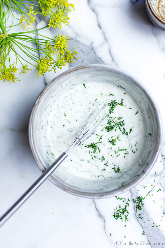 Creamy dill dressing in a bowl with a whisk.