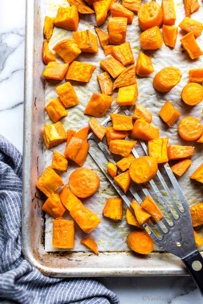 Roasted sweet potatoes and carrots on a sheet pan.