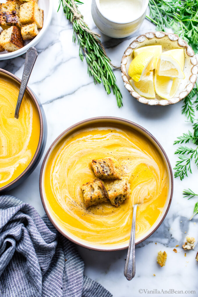 Two bowls of sweet potato carrot soup garnished with croutons.