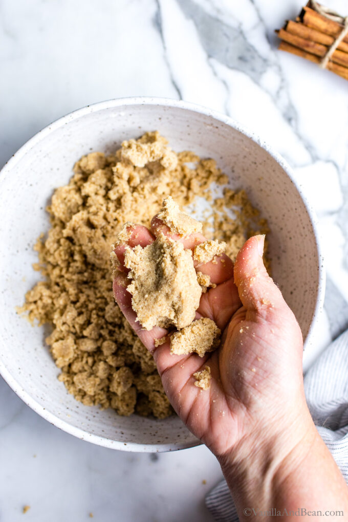 Vegan cinnamon crumble pressed together in a hand.