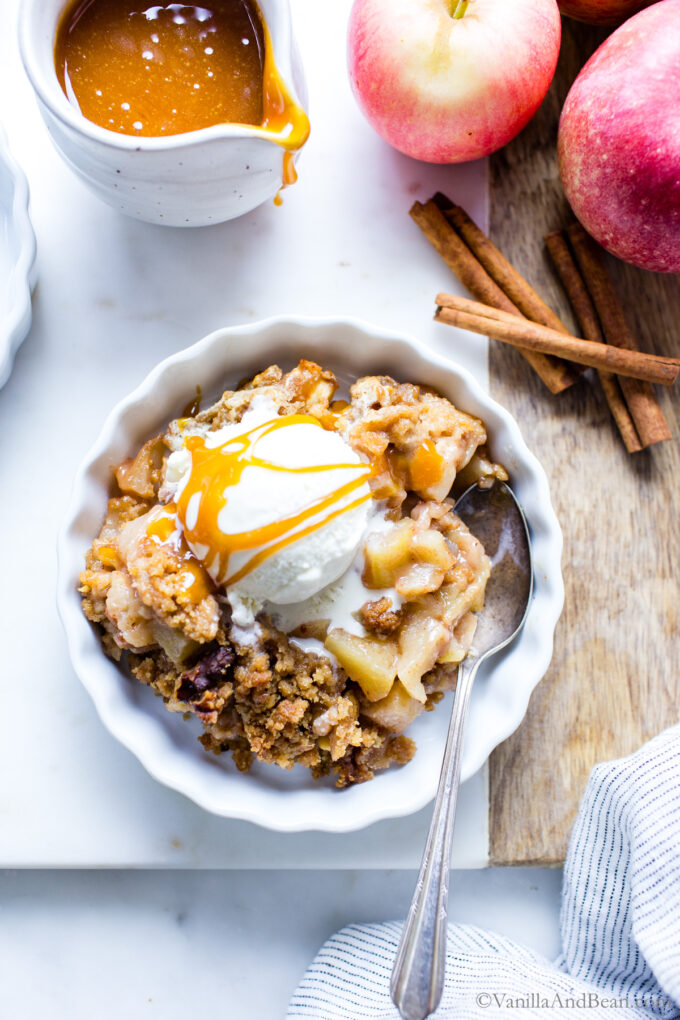 Simple vegan crumble in a single serving dish with ice cream and caramel sauce on top. 