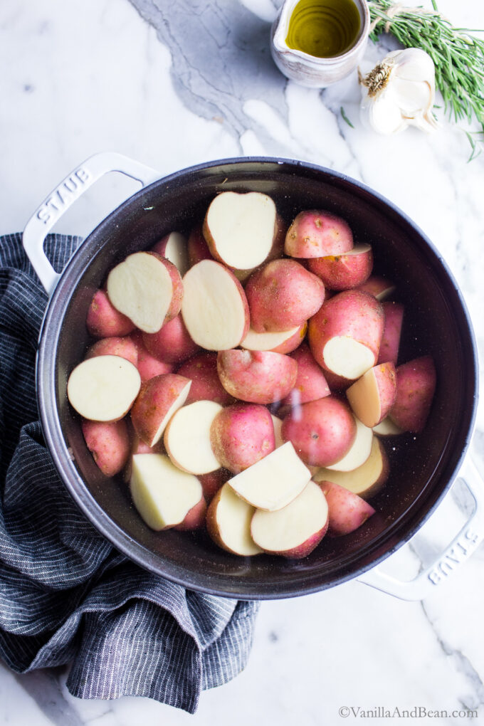 Red new potatoes in a Dutch oven filled with water.