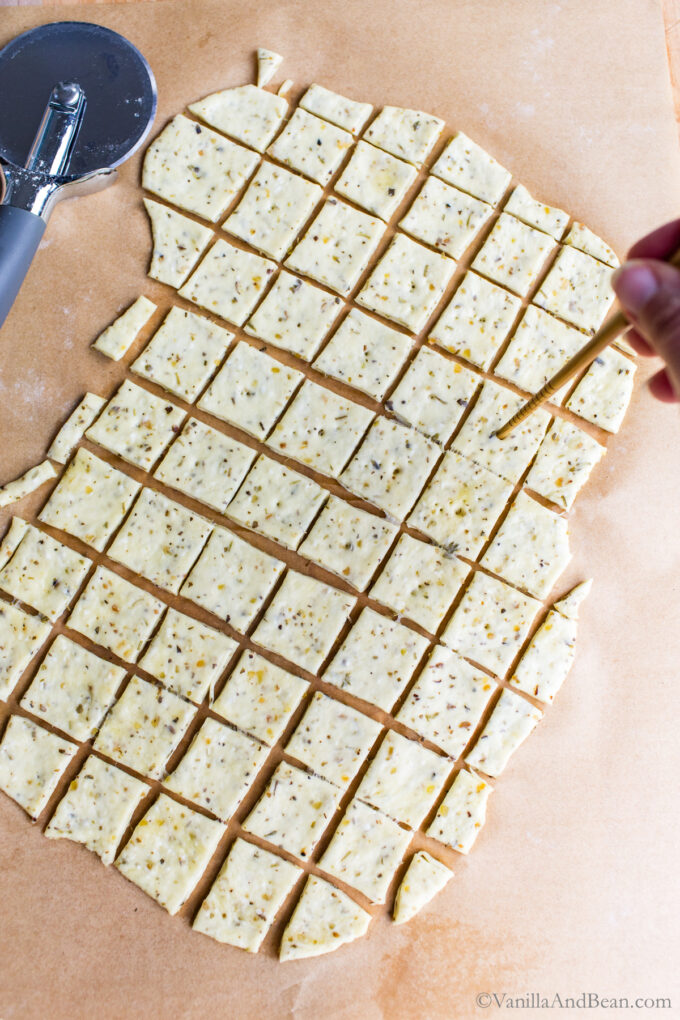 Docking sourdough discard cracker dough with a chopstick.