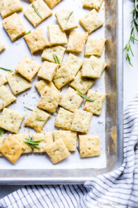 Olive oil sourdough discard crackers with herbs on a sheet pan.