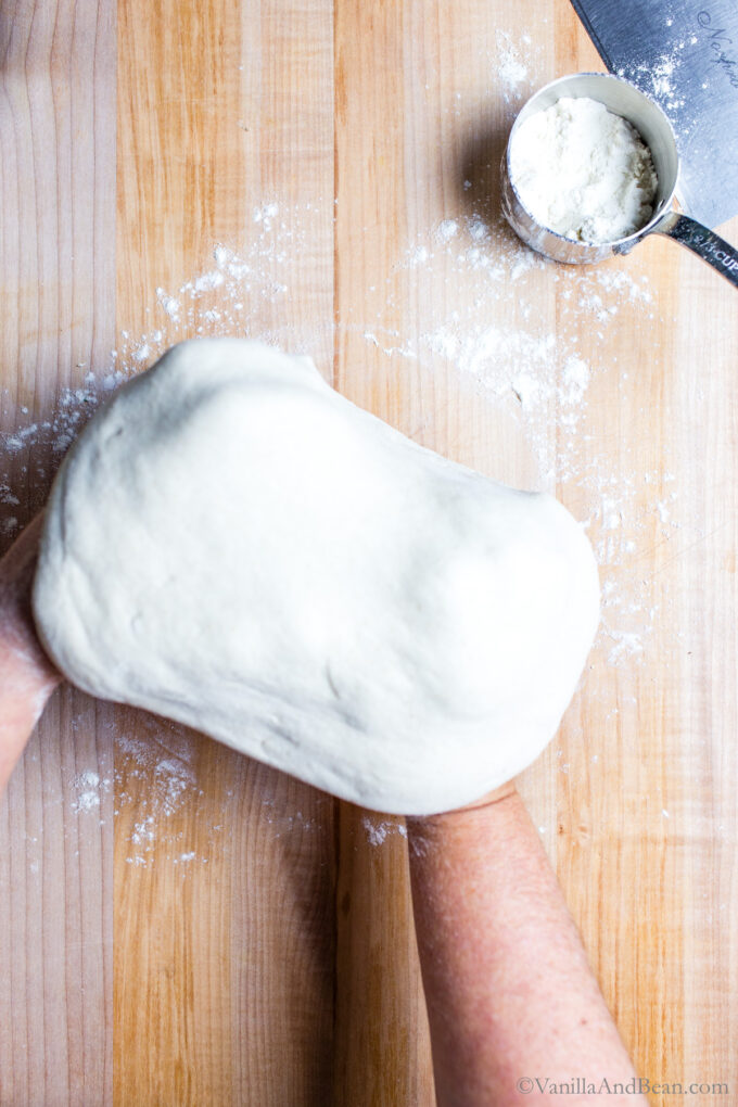 Gently using the back of hands to shape sourdough discard pizza dough.