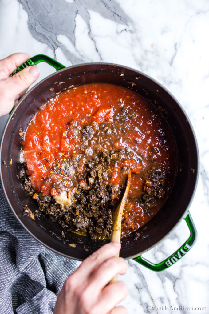Stirring bolognese sauce in a Dutch oven.
