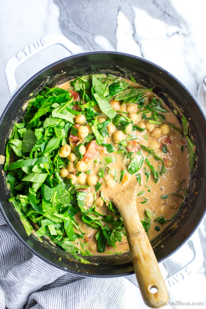 Stirring the chickpea curry with spinach.