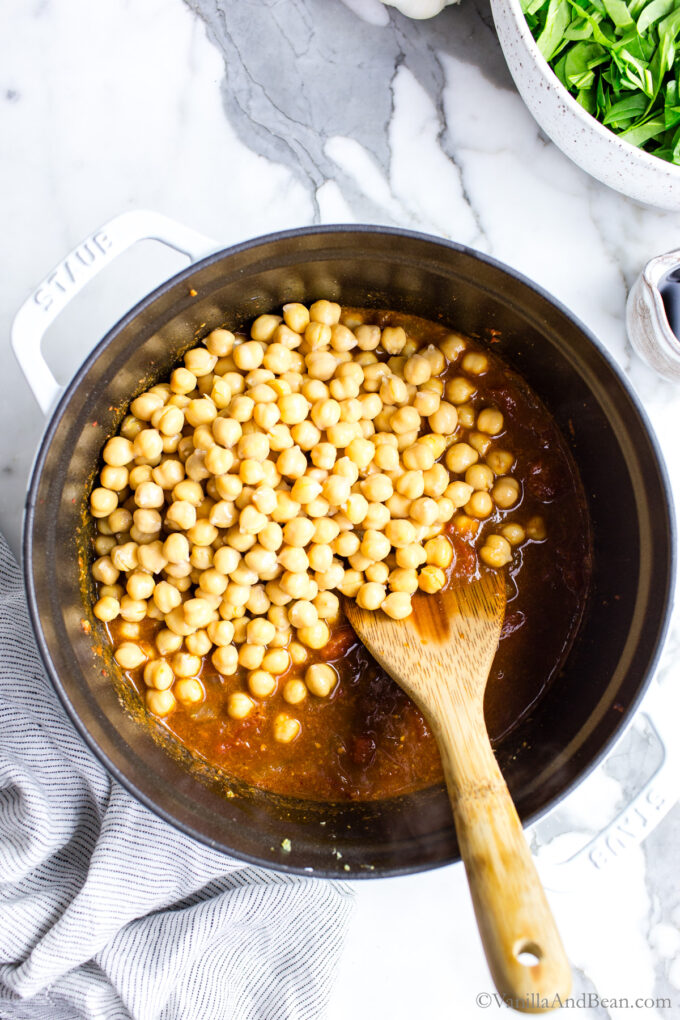 Chickpeas in a Dutch oven with a spoon.