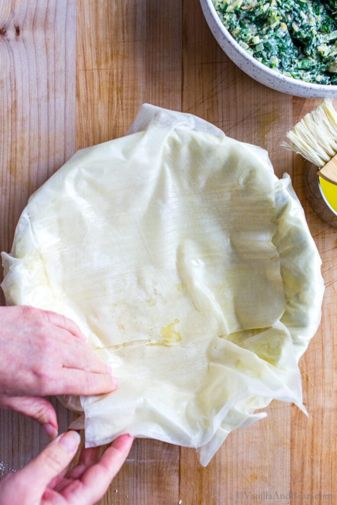 Arranging phyllo dough in a pie pan.