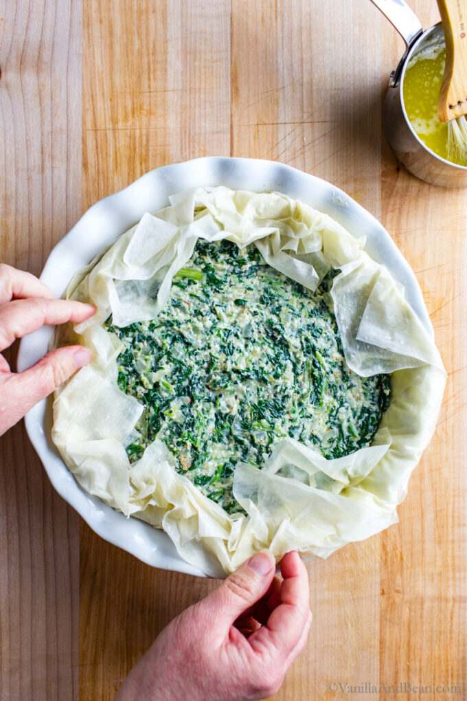 Phyllo dough filled with spinach mixture and phyllo dough folded around the edges of the pie.