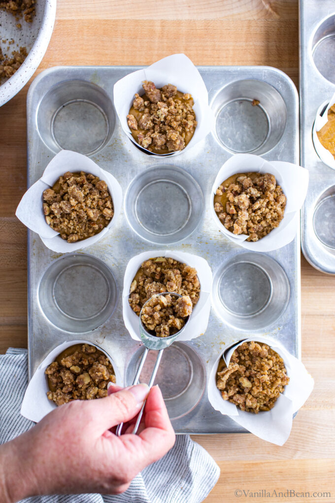 Adding streusel to the tops of the sourdough discard pumpkin muffins in tulip cups.