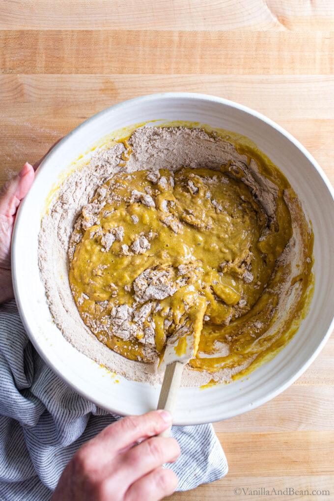 Mixing sourdough discard pumpkin muffins batter in a bowl.