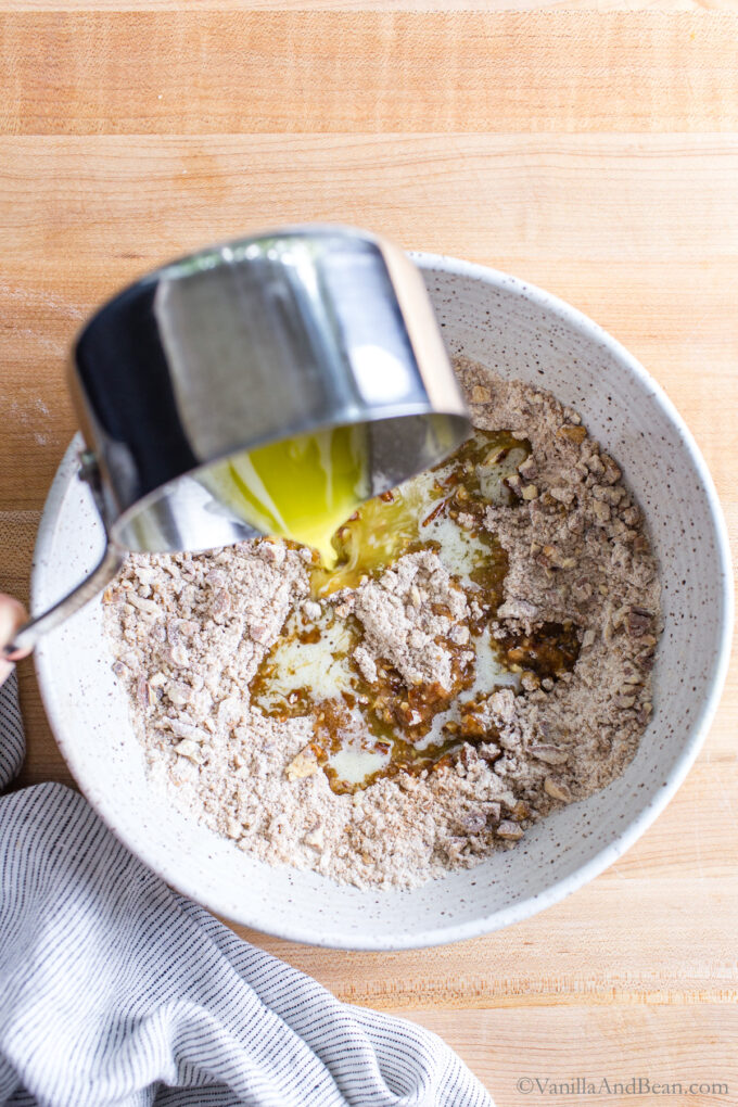 Pouring butter over the crumble streusel topping in a bowl.