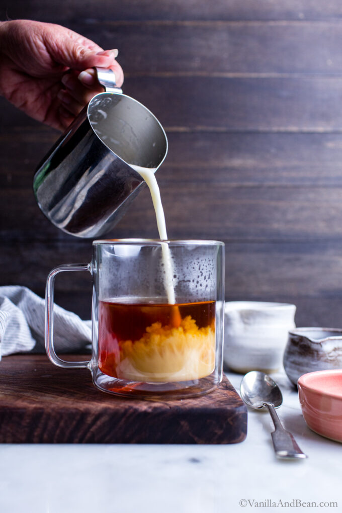 Pouring hot milk into hot chai tea.