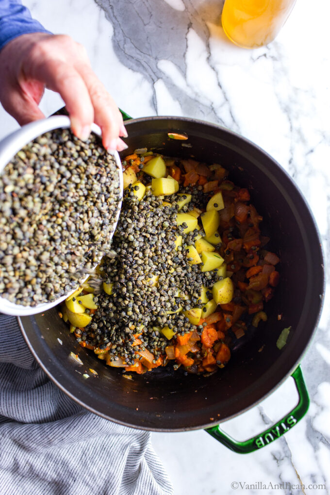 Adding potatoes and french lentils to the soup pot.