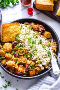 Veggie gumbo with okra in a bowl with a side of rice and cornbread.
