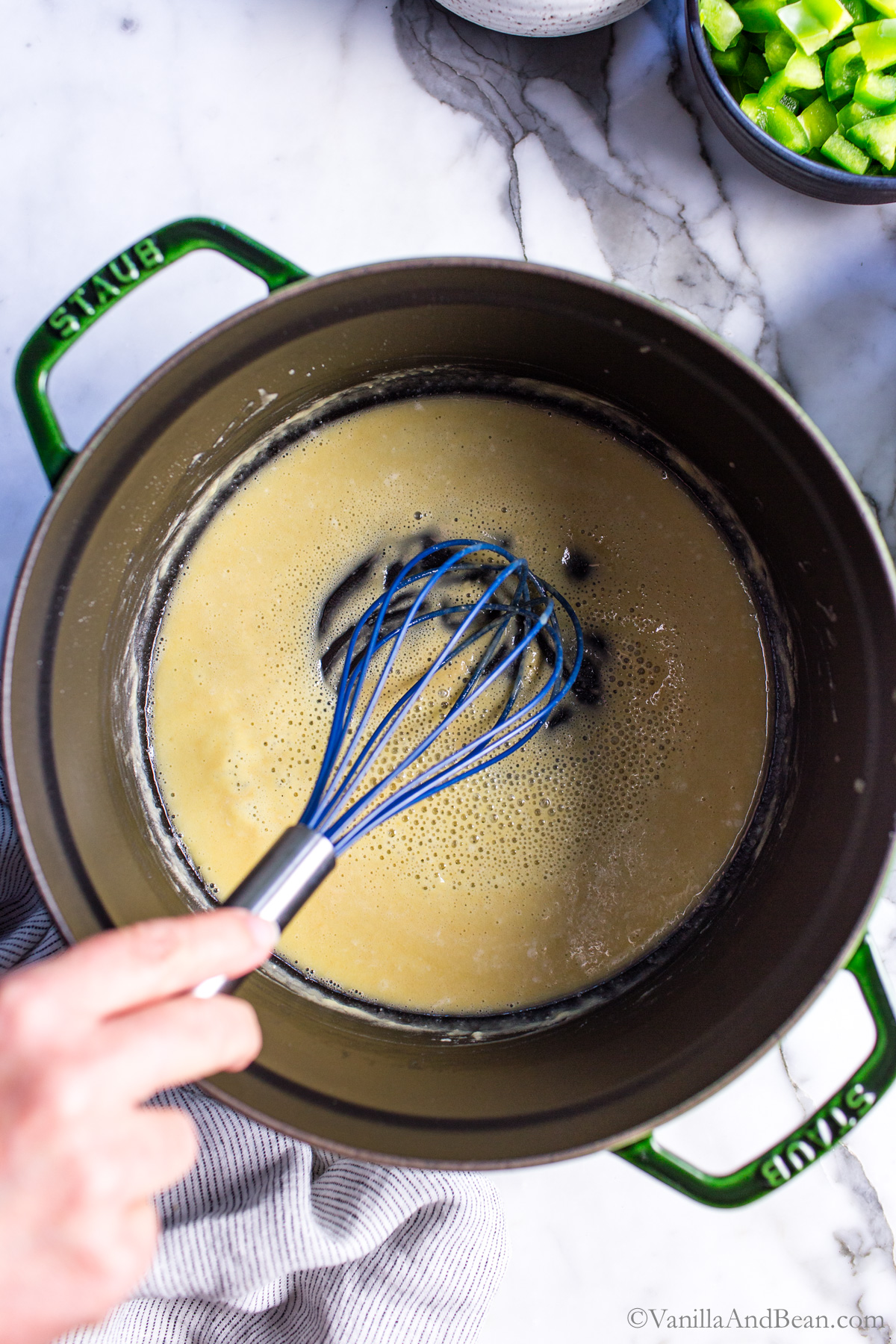 Butter in flour in a Dutch oven being whisked. It's of a golden color. A roux is being made.