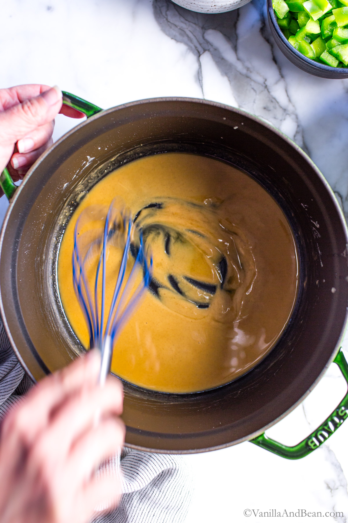 Butter in flour in a Dutch oven being whisked. It's of a peanut butter/golden brown color. A roux is being made.