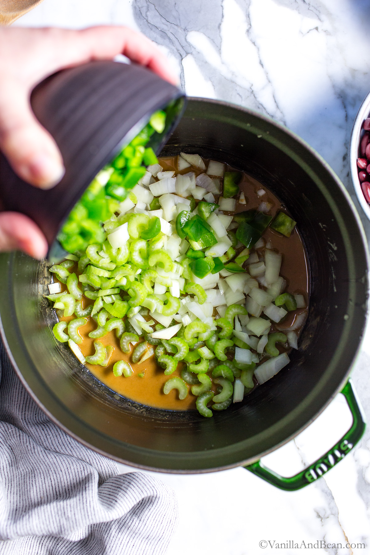 Diced onions, bell pepper and celery and added to the Dutch oven, over the roux.