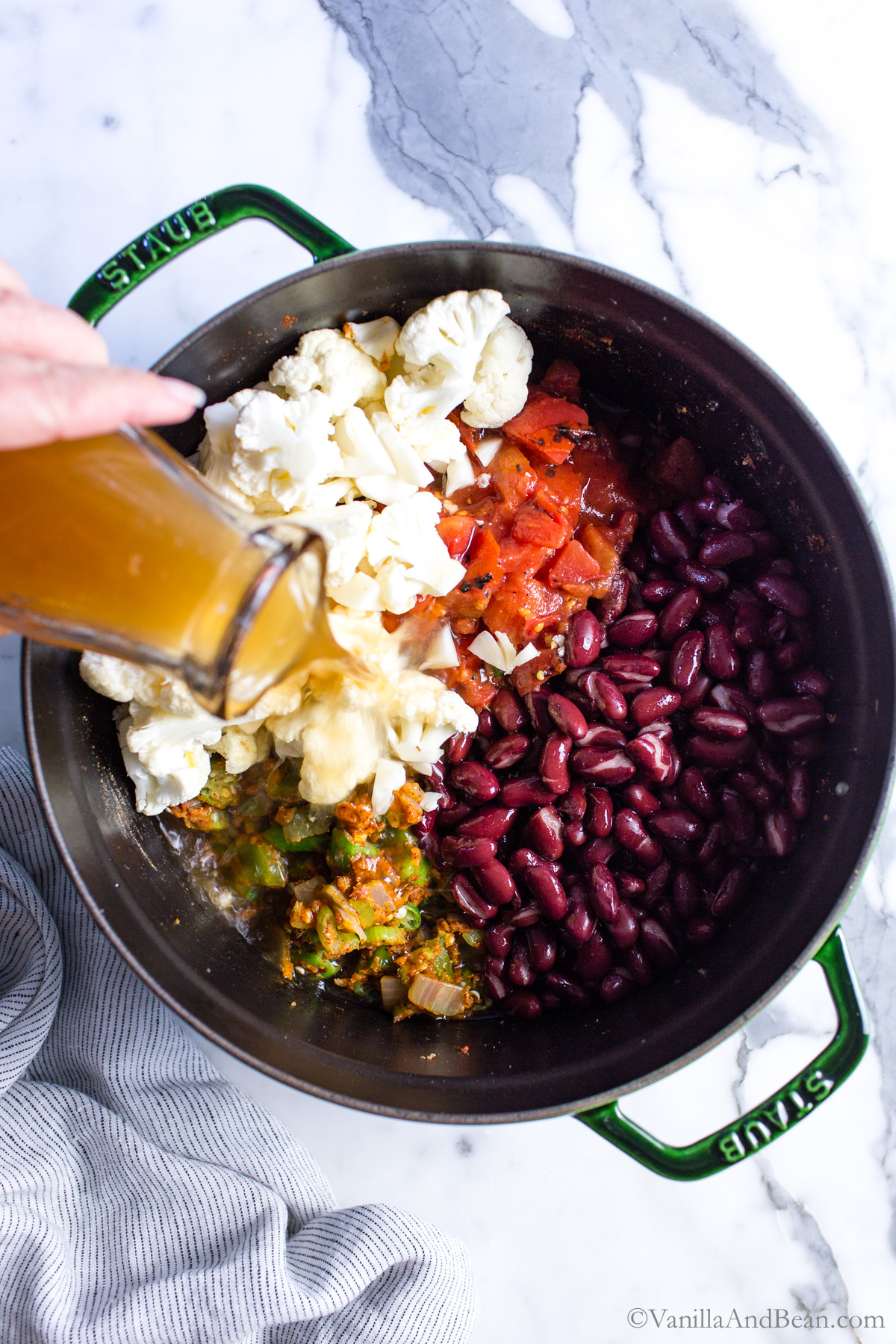 To the Dutch oven with the veggie gumbo, kidney beans, tomatoes and cauliflower are added.