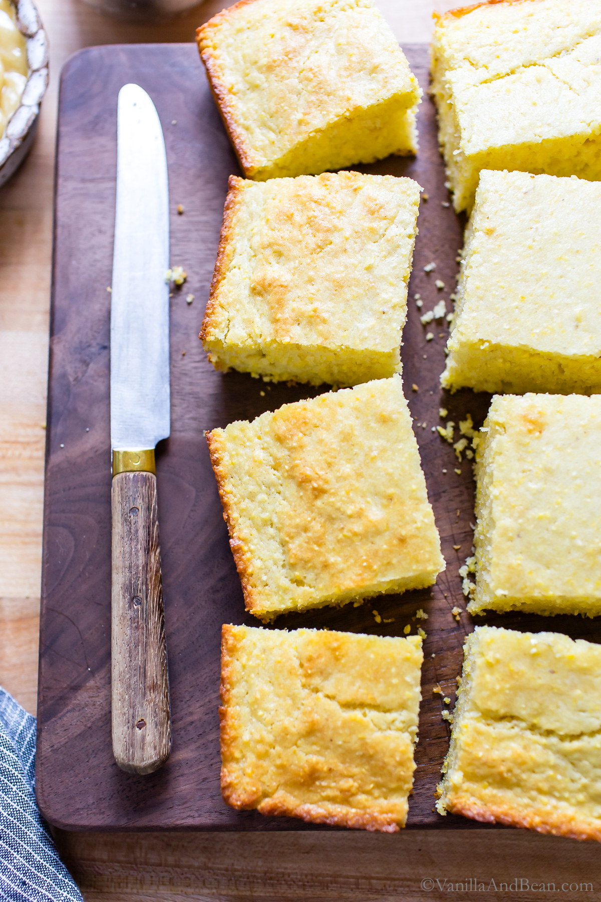 Sourdough Discard Cornbread cut into 2 inch squares on a cutting board, overhead picture.