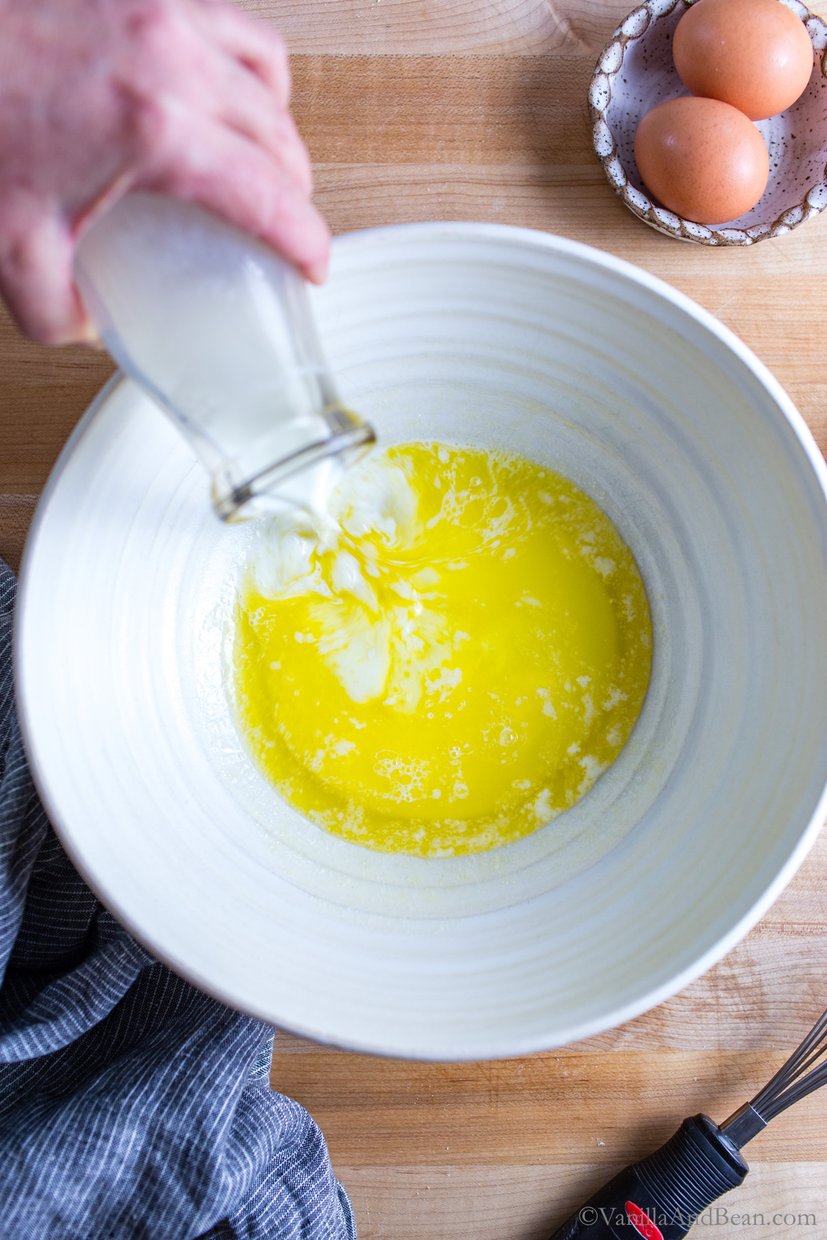Adding milk to melted butter in a bowl.