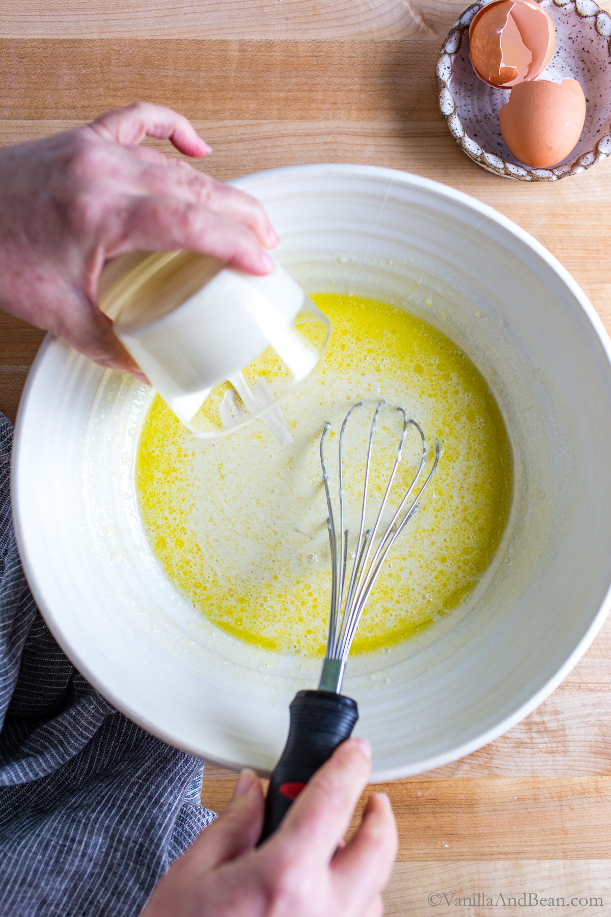 Adding sourdough discard to the egg mixture in a bowl.