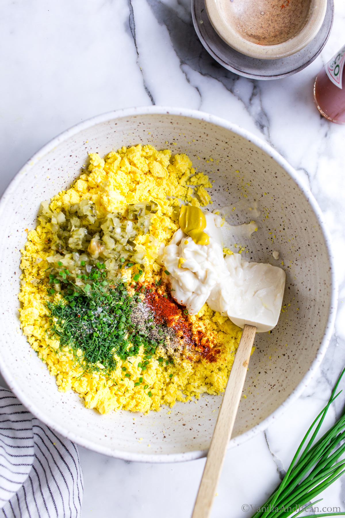 Hard cooked egg yolks in a bowl with other recipe ingredients and a stir spatula.