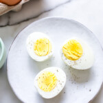 Hard cooked steamed eggs sliced in half on a plate.