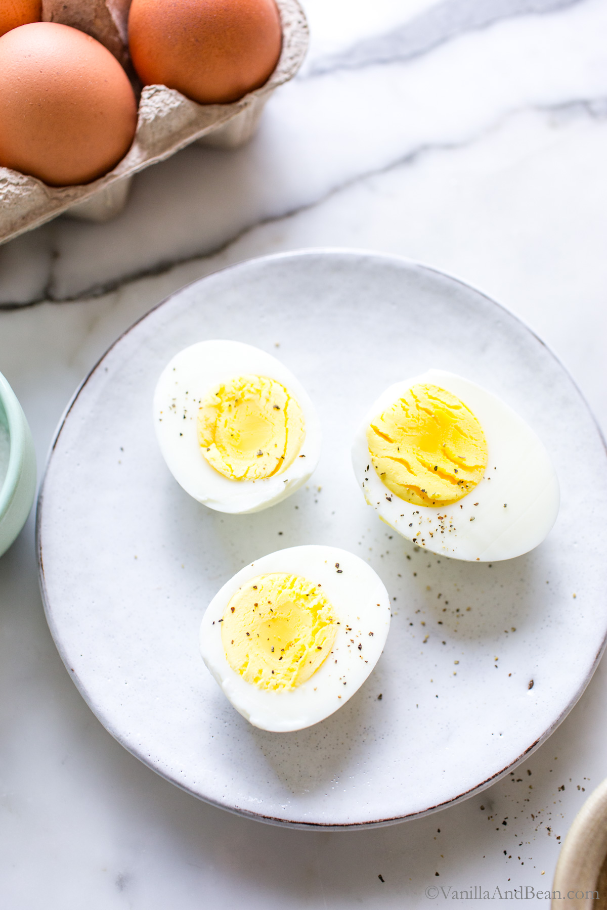 Hard cooked steamed eggs sliced in half on a plate.