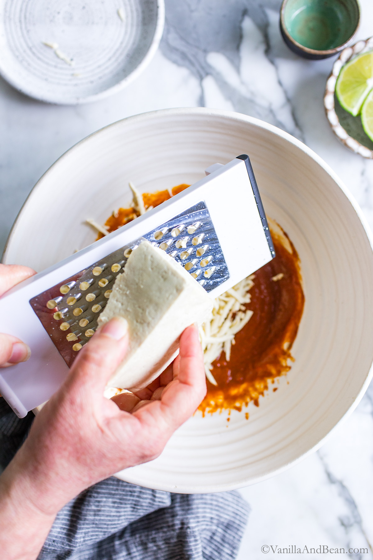 Shredding Tofu into a bowl with seasonings.