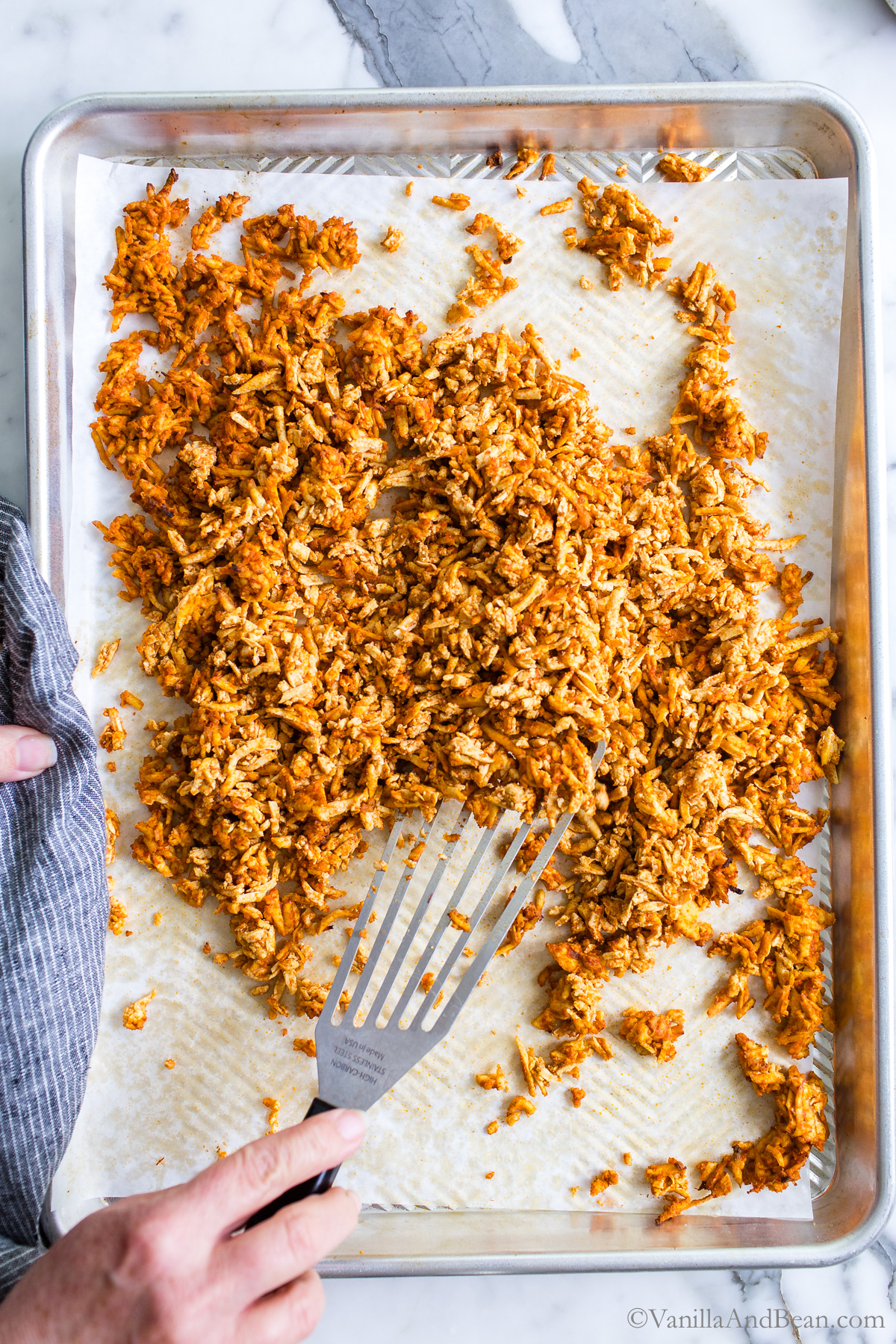 Stirring Tex Mex Shredded Tofu on a sheet pan.