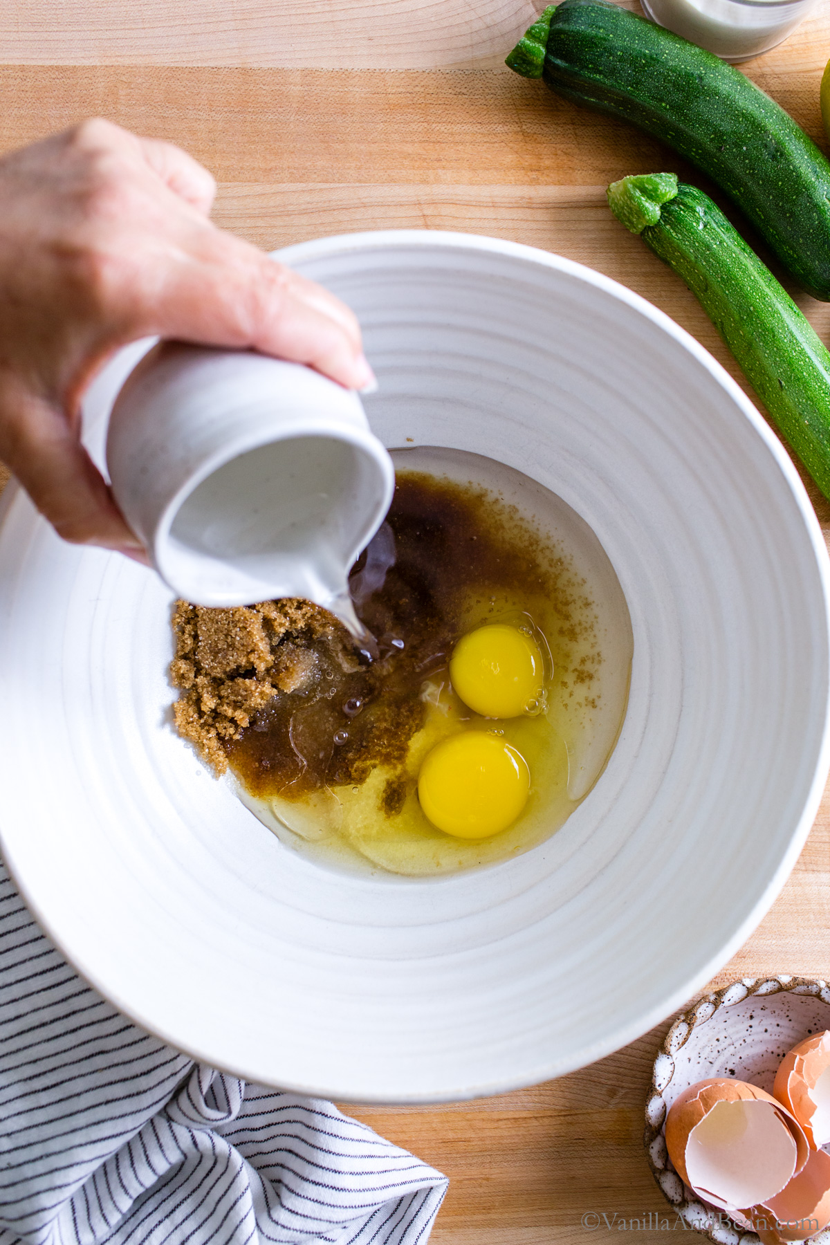 Pouring the coconut oil into the wet ingredients in a bowl.