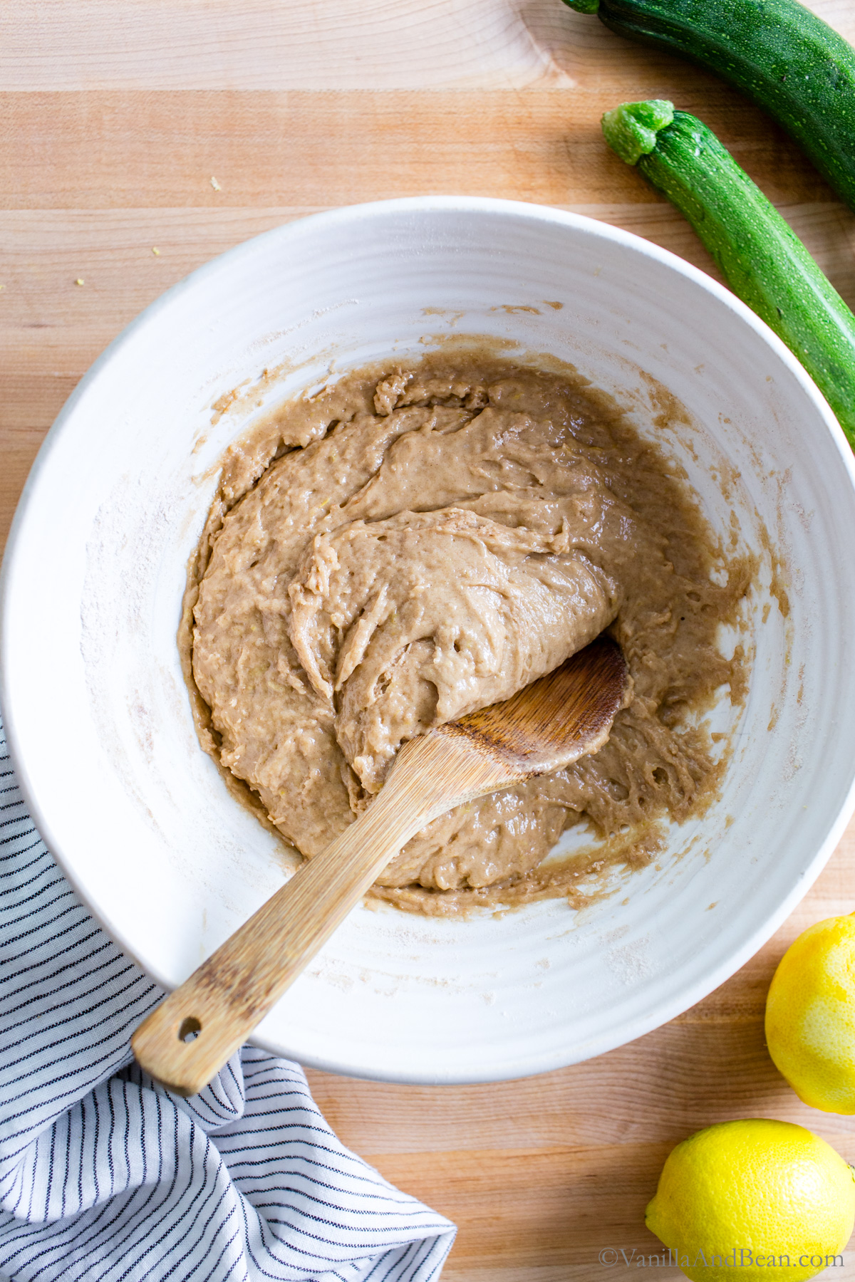 Zucchini bread batter in a bowl with a wood spoon.