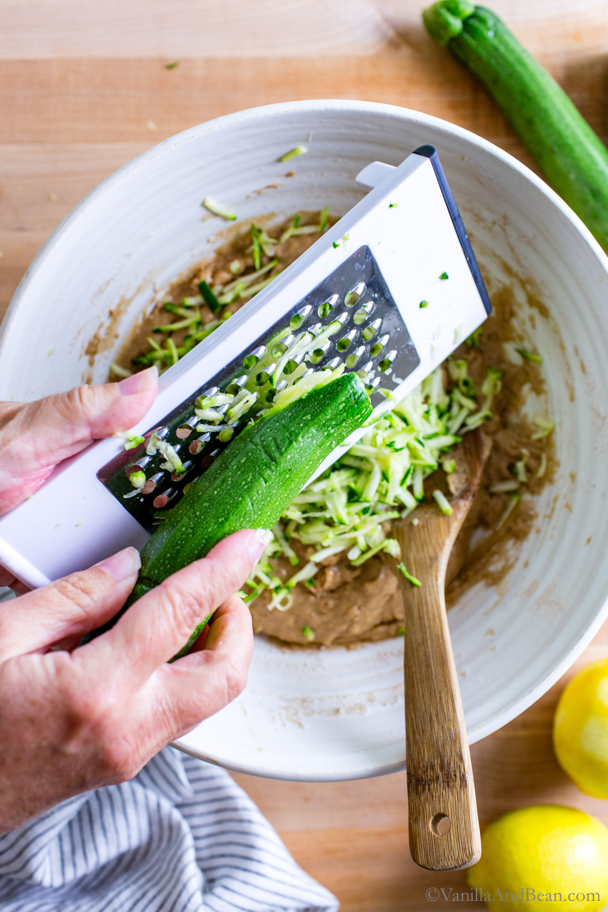 Grating the zucchini into the wet ingredients.