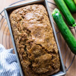 Baked sourdough zucchini bread on a cooling rack in a loaf pan.