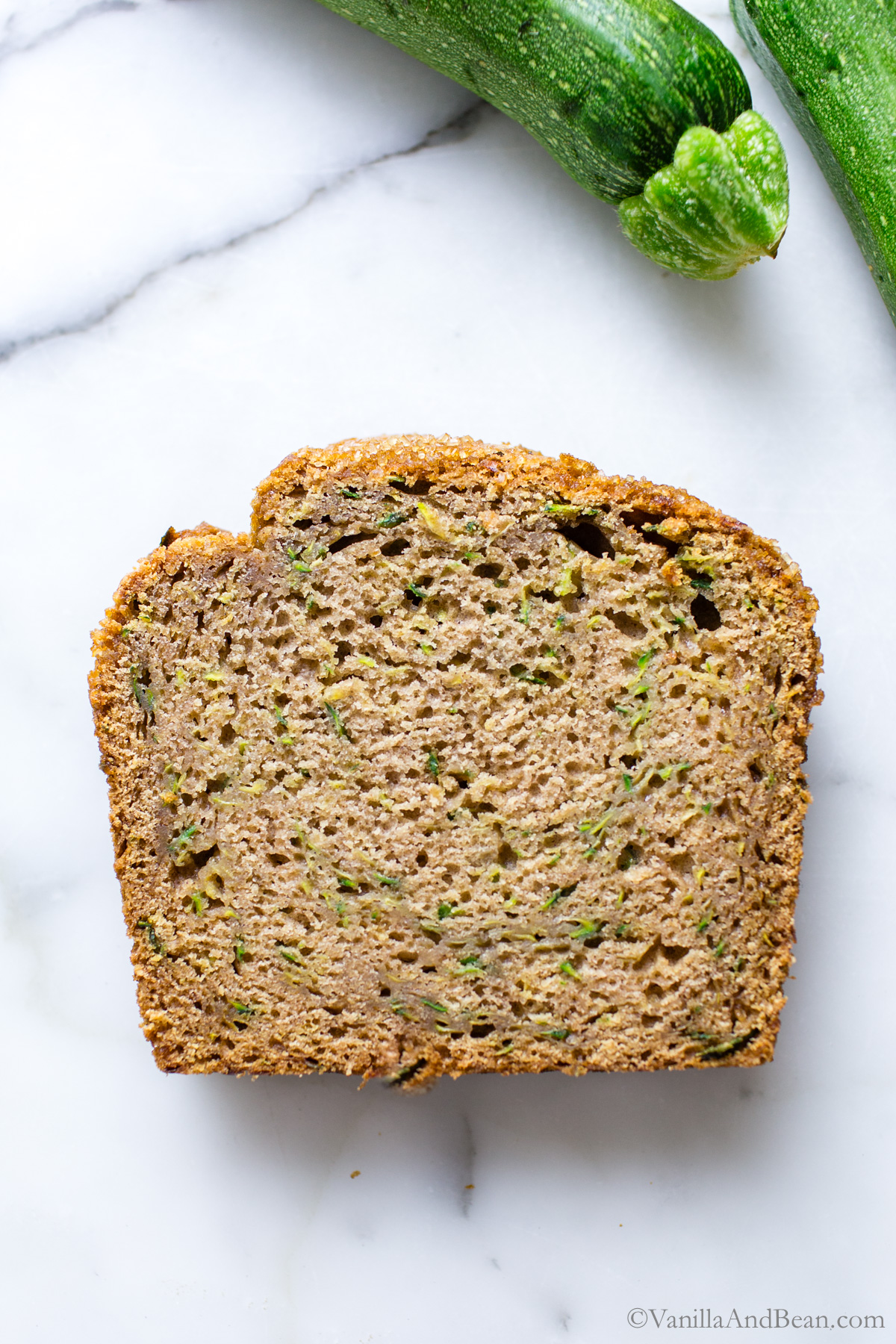 A slice of baked sourdough zucchini bread on a marble table.