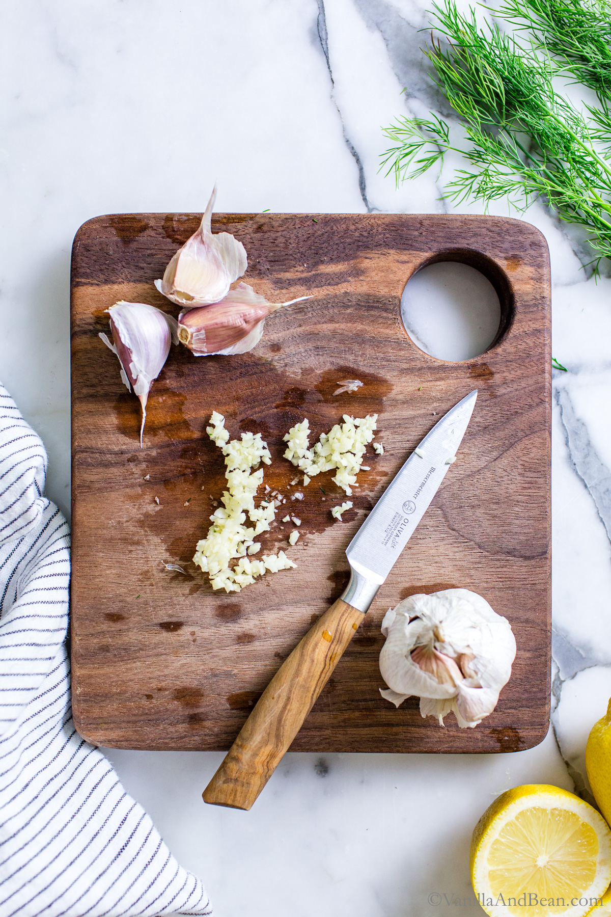 Chopped garlic on a cutting board with a knife.